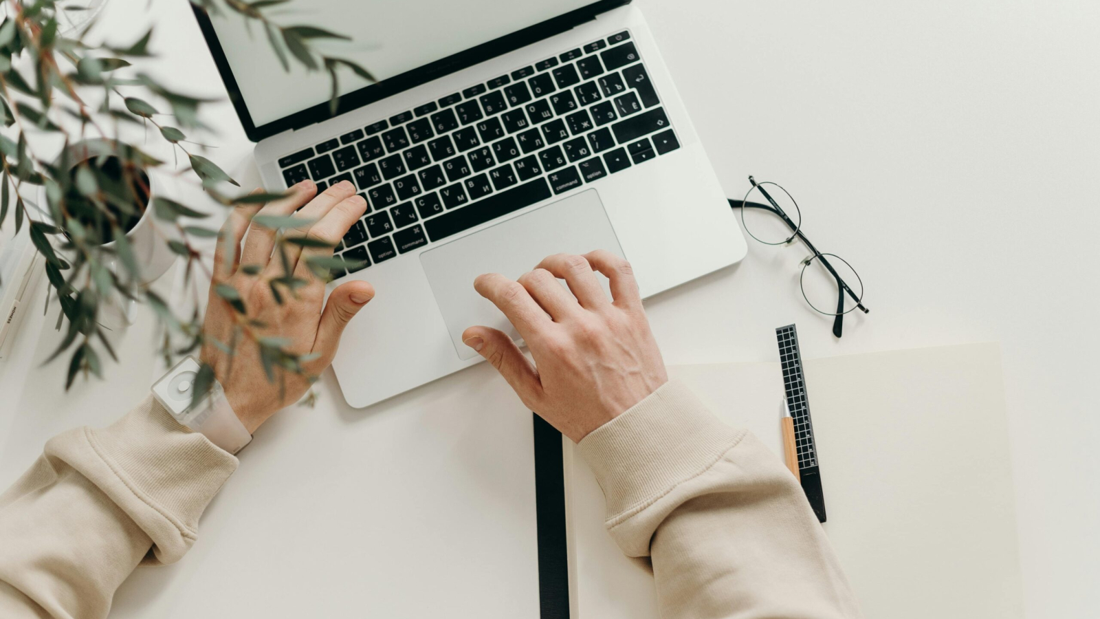 Free An overhead view of a person working on a laptop in a minimalist home office setting. Stock Photo